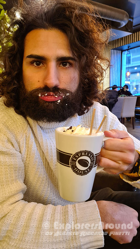 alberto riccardo finetti, creatore di explorers around, che beve una cioccolata sporcandosi la barba da espresso house in Copenaghen Danimarca