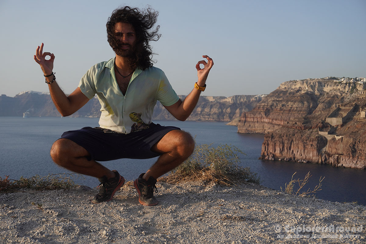 alberto riccardo finetti in posa con dietro la caldera di santorini e i villaggi di fira oia all'orizzonte explorers around